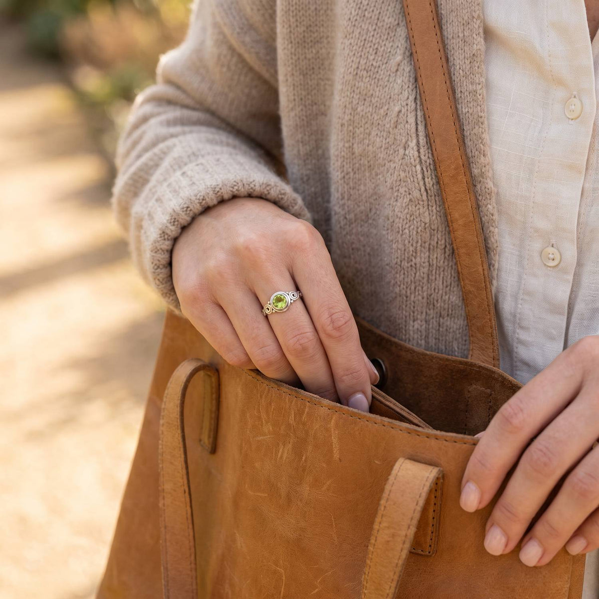Frau trägt Silberring mit Peridot beim Griff in eine Tasche