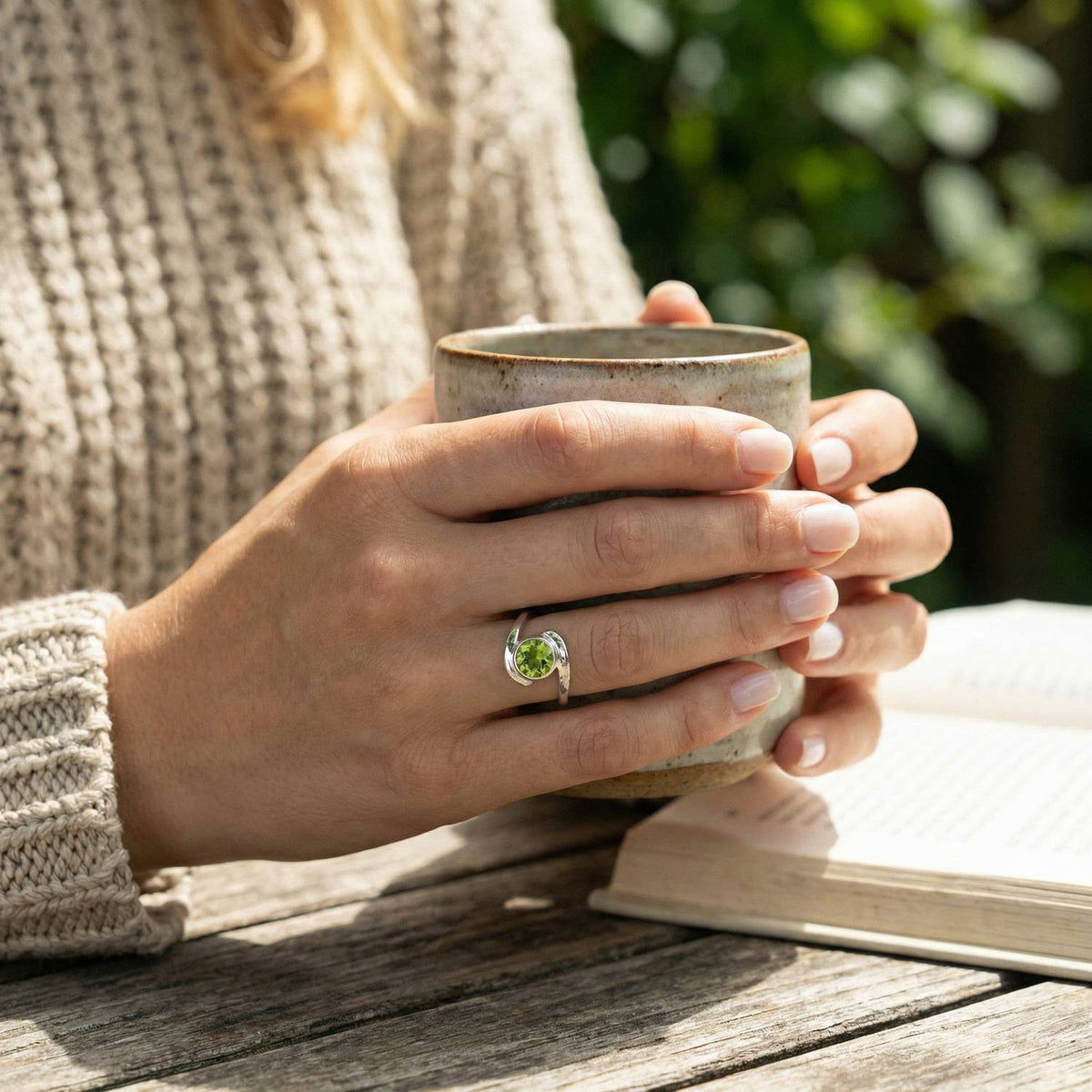 Peridotring aus Silber getragen beim Lesen mit einer Tasse
