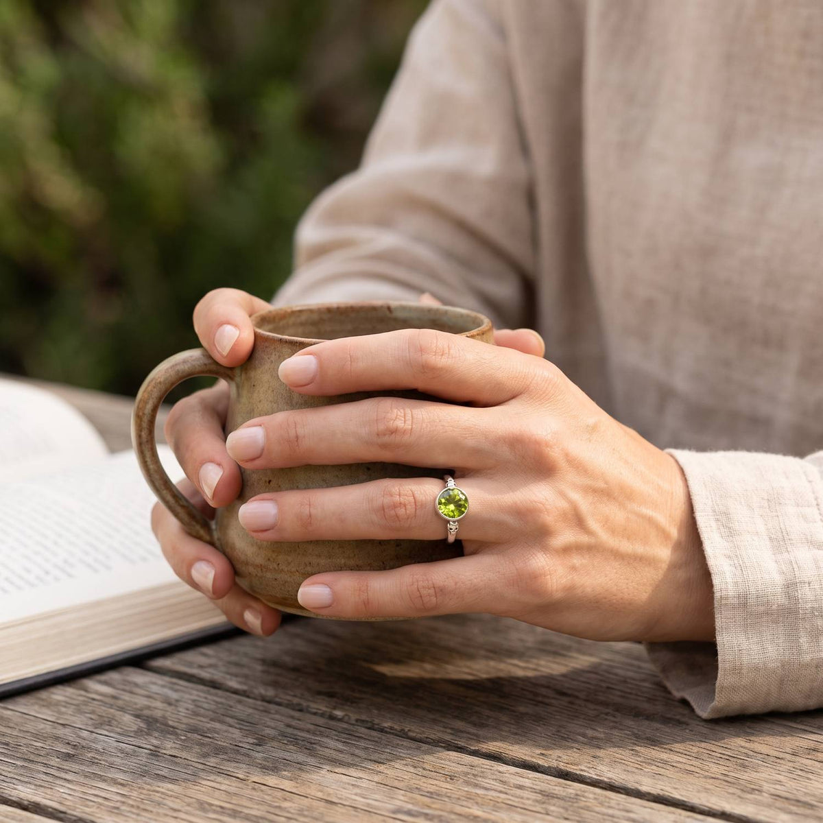 Peridotring aus Silber getragen beim Lesen mit einer Tasse