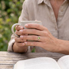 [KI] Peridotring aus Silber getragen beim Lesen mit einer Tasse
