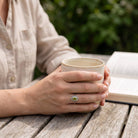 [KI] Peridotring aus Silber getragen beim Lesen mit einer Tasse