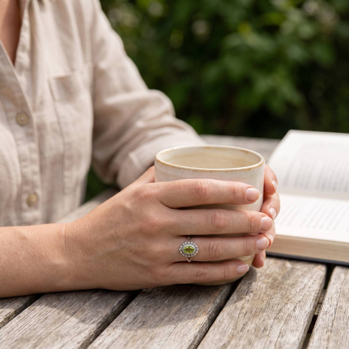 Peridotring aus Silber getragen beim Lesen mit einer Tasse