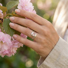 [KI] Silberring mit Rosenquarz an der Hand zwischen Blumen