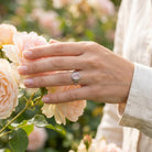 [KI] Silberring mit Rosenquarz an der Hand zwischen Blumen