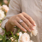 [KI] Silberring mit Rosenquarz an der Hand zwischen Blumen