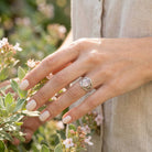 [KI] Silberring mit Rosenquarz an der Hand zwischen Blumen