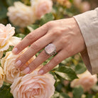 [KI] Silberring mit Rosenquarz an der Hand zwischen Blumen