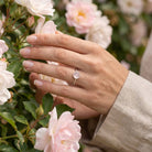 [KI] Silberring mit Rosenquarz an der Hand zwischen Blumen