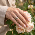[KI] Silberring mit Rosenquarz an der Hand zwischen Blumen