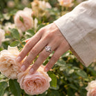 [KI] Silberring mit Rosenquarz an der Hand zwischen Blumen