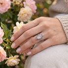 [KI] Silberring mit Rosenquarz an der Hand zwischen Blumen