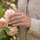 [KI] Silberring mit Rosenquarz an der Hand zwischen Blumen