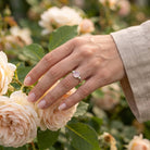 [KI] Silberring mit Rosenquarz an der Hand zwischen Blumen