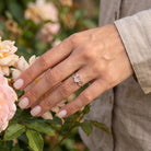 [KI] Silberring mit Rosenquarz an der Hand zwischen Blumen