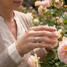 [KI] Silberring mit Rosenquarz an der Hand zwischen Blumen