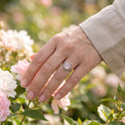 [KI] Silberring mit Rosenquarz an der Hand zwischen Blumen