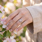 [KI] Silberring mit Rosenquarz an der Hand zwischen Blumen