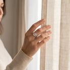 [KI] Frau trägt einen Rosenquarzring aus Silber am Fenster