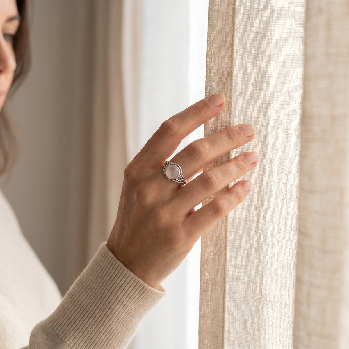 Frau trägt einen Rosenquarzring aus Silber am Fenster