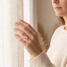 [KI] Frau trägt einen Rosenquarzring aus Silber am Fenster