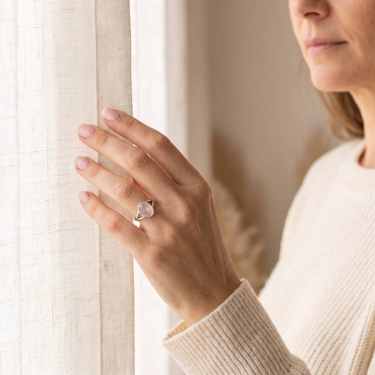 Frau trägt einen Rosenquarzring aus Silber am Fenster