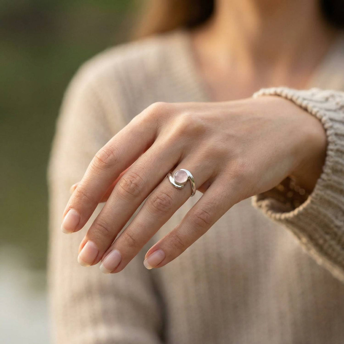 Rosenquarzring aus Silber getragen an der Hand im Freien