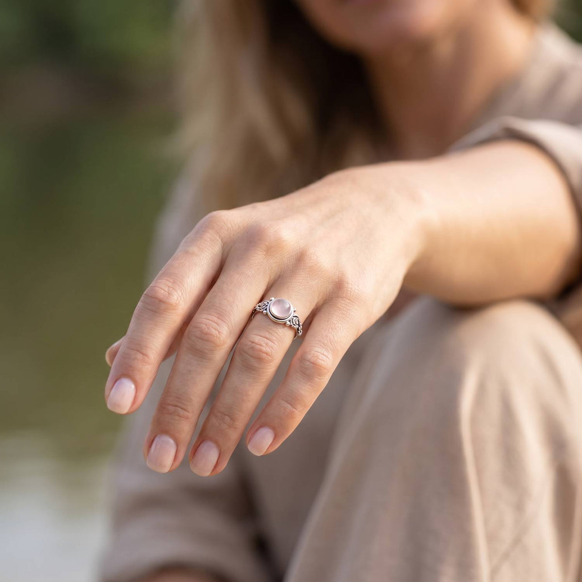 Rosenquarzring aus Silber getragen an der Hand im Freien