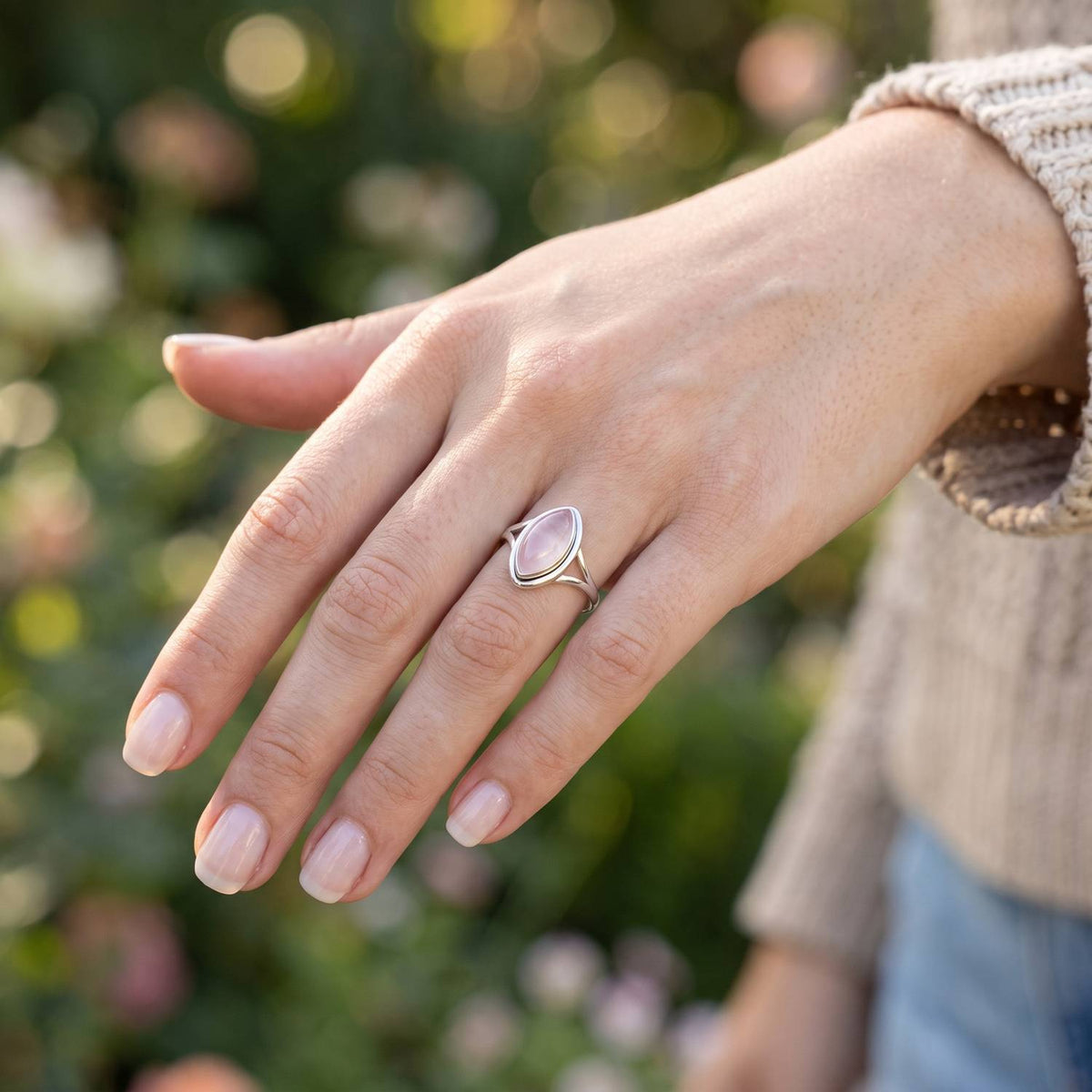 Rosenquarzring aus Silber getragen an der Hand im Freien