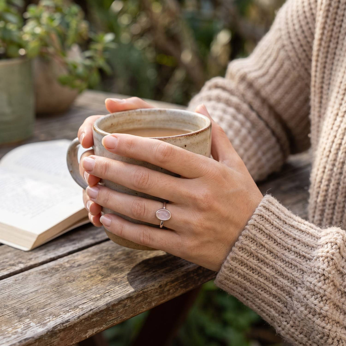 Rosenquarzring aus Silber getragen beim Lesen mit einer Tasse