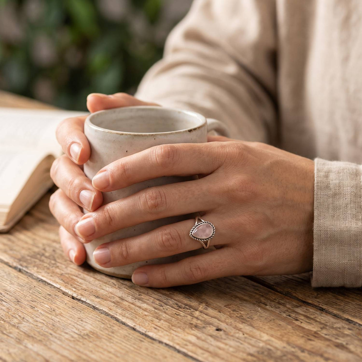 Rosenquarzring aus Silber getragen beim Lesen mit einer Tasse