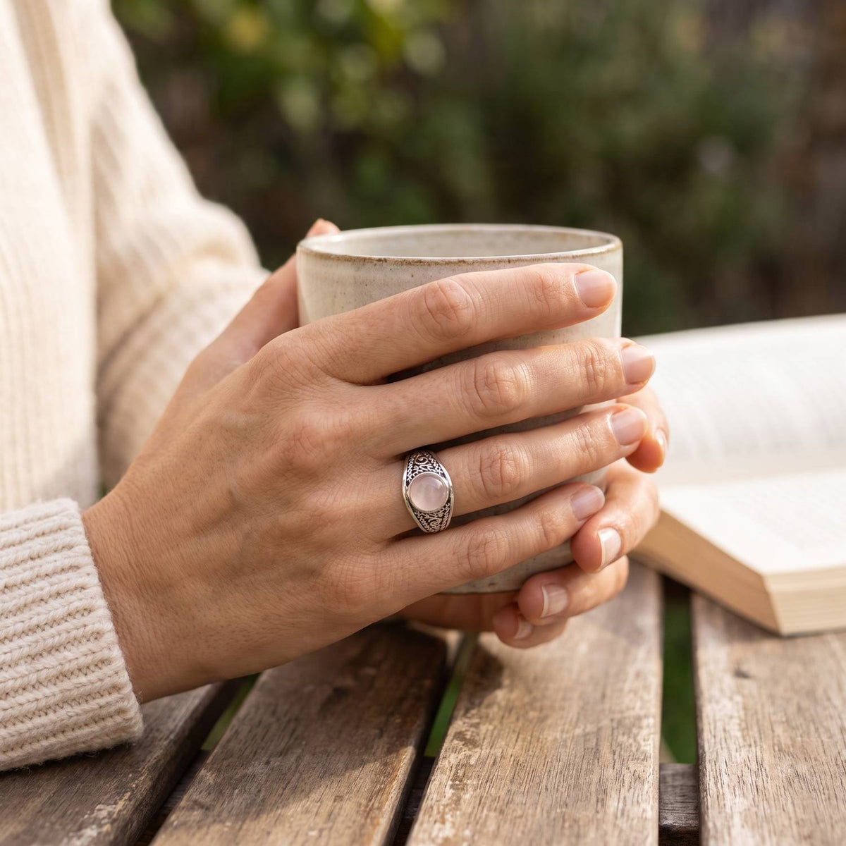 Rosenquarzring aus Silber getragen beim Lesen mit einer Tasse