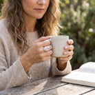 [KI] Rosenquarzring aus Silber getragen beim Lesen mit einer Tasse