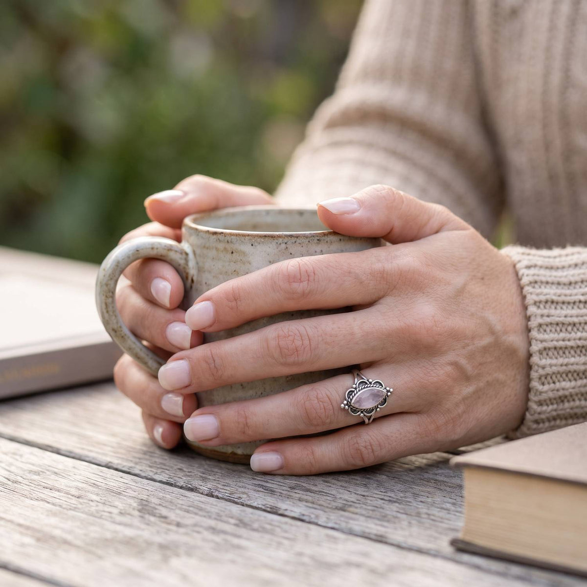 Rosenquarzring aus Silber getragen beim Lesen mit einer Tasse