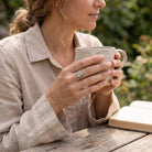 [KI] Rosenquarzring aus Silber getragen beim Lesen mit einer Tasse