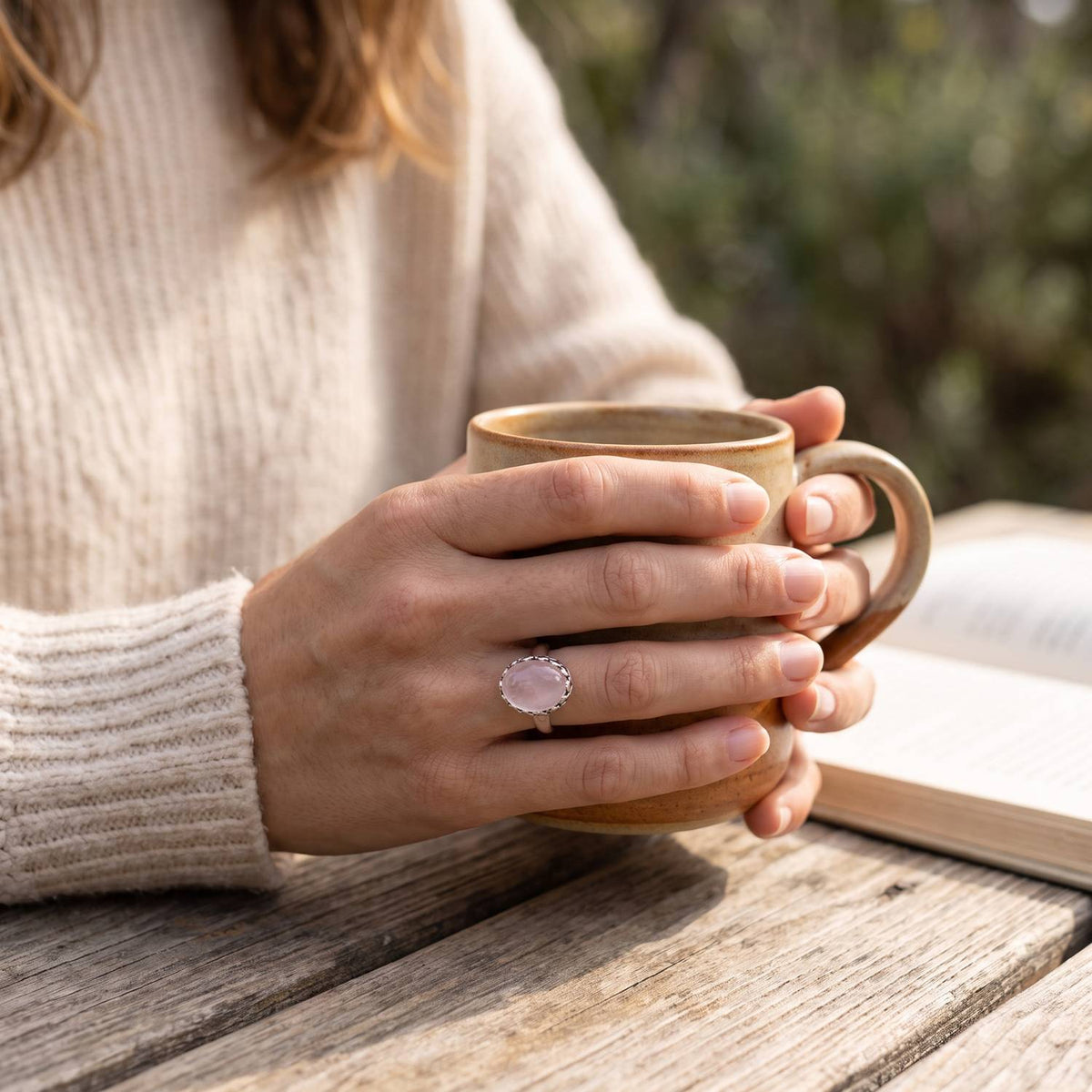 Rosenquarzring aus Silber getragen beim Lesen mit einer Tasse