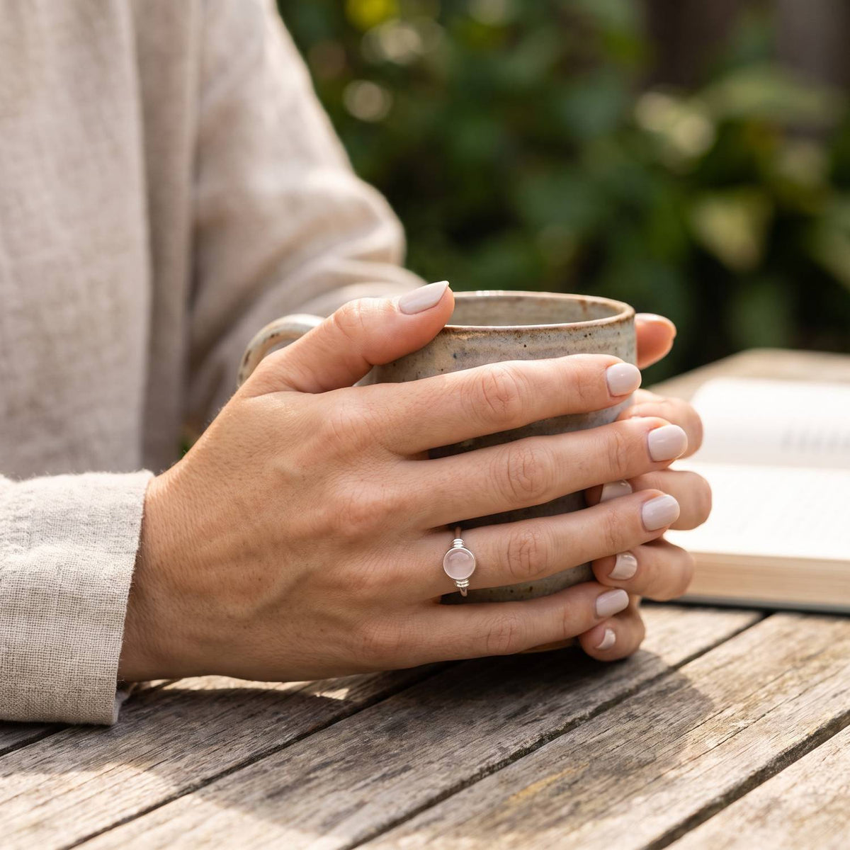 Rosenquarzring aus Silber getragen beim Lesen mit einer Tasse