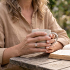 [KI] Rosenquarzring aus Silber getragen beim Lesen mit einer Tasse