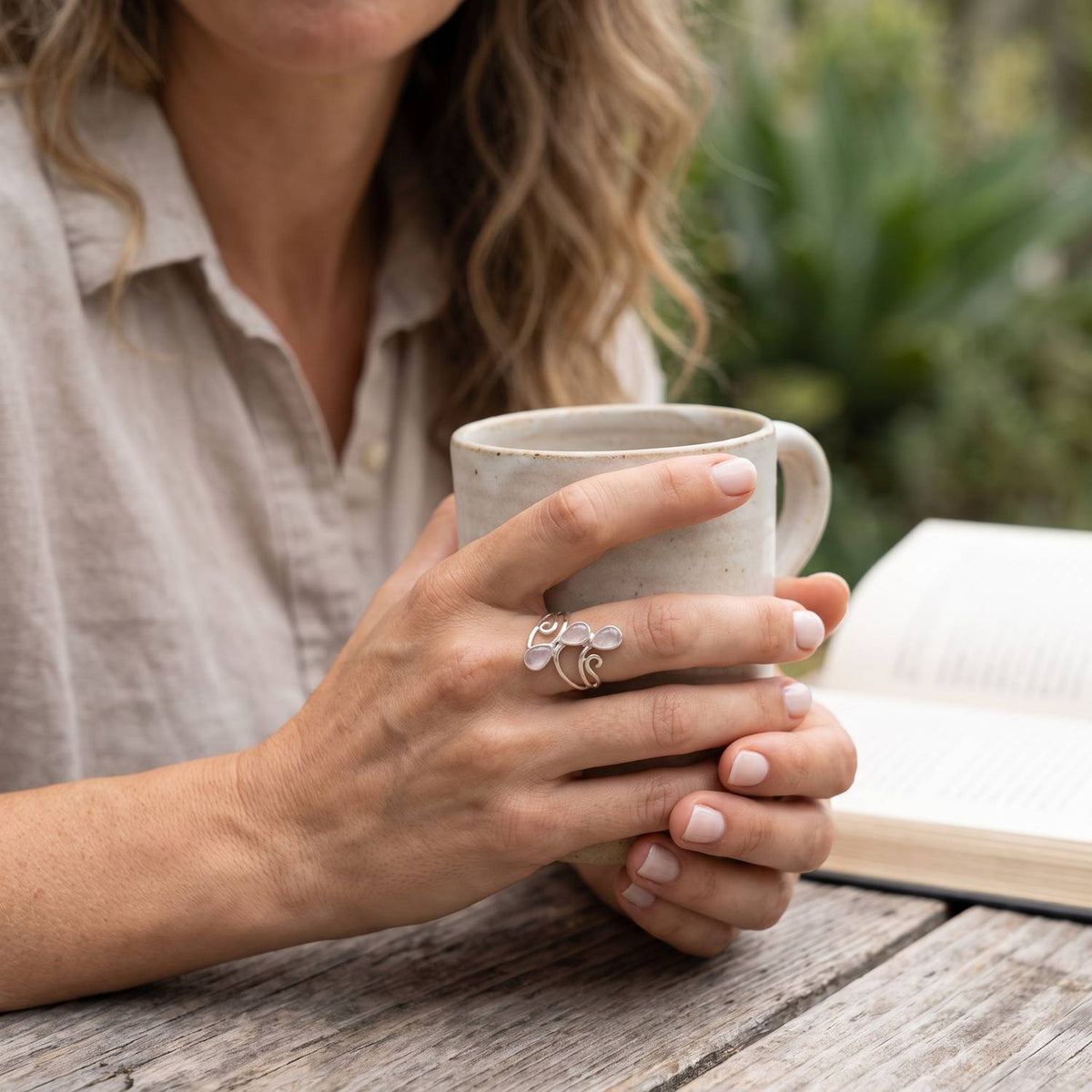 Rosenquarzring aus Silber getragen beim Lesen mit einer Tasse