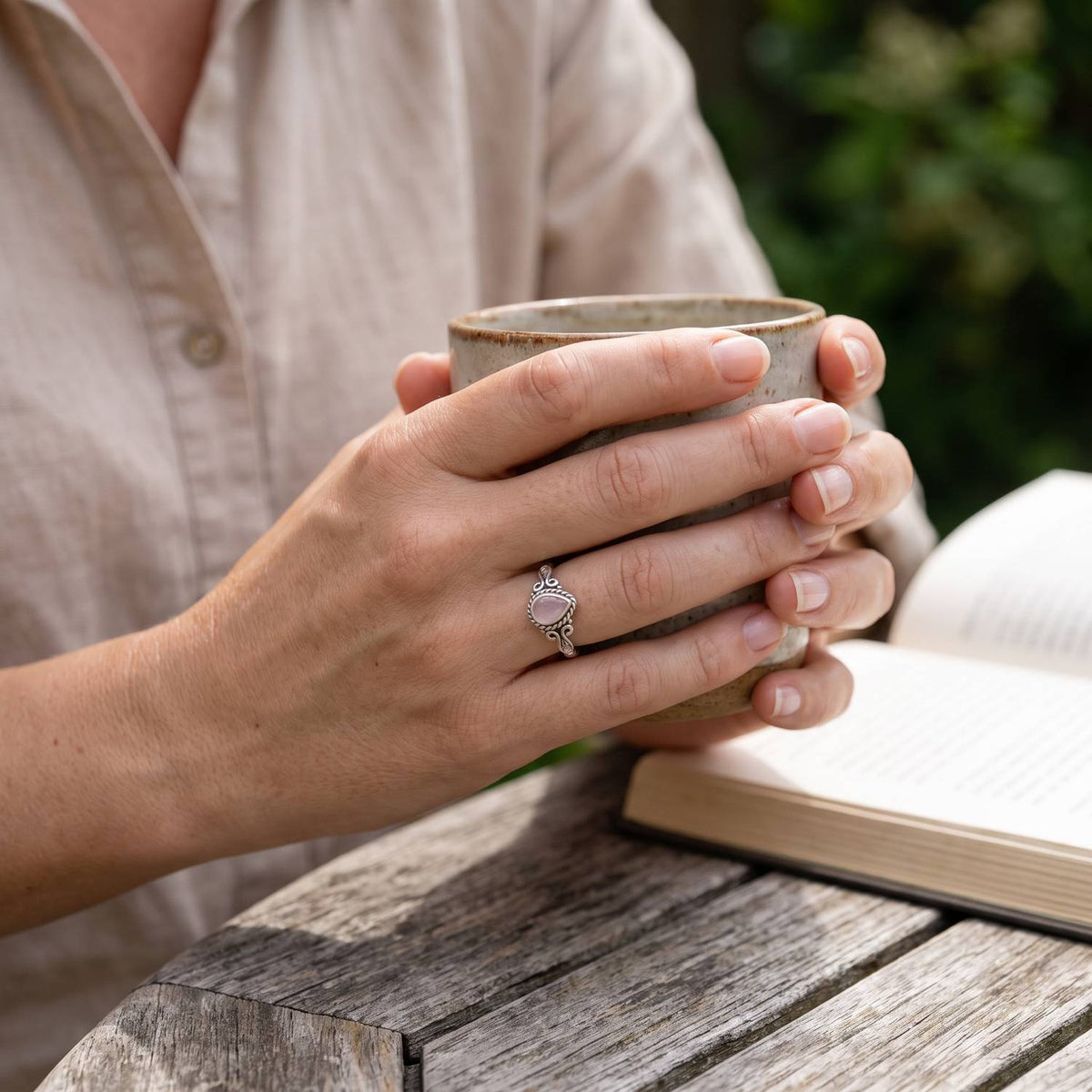 Rosenquarzring aus Silber getragen beim Lesen mit einer Tasse