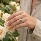 [KI] Silberring mit Tigerauge an der Hand zwischen Blumen