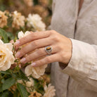 [KI] Silberring mit Tigerauge an der Hand zwischen Blumen