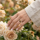 [KI] Silberring mit Tigerauge an der Hand zwischen Blumen