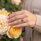 [KI] Silberring mit Tigerauge an der Hand zwischen Blumen