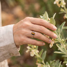 [KI] Silberring mit Tigerauge an der Hand zwischen Blumen