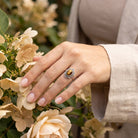 [KI] Silberring mit Tigerauge an der Hand zwischen Blumen
