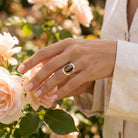 [KI] Silberring mit Tigerauge an der Hand zwischen Blumen