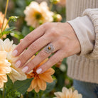 [KI] Silberring mit Tigerauge an der Hand zwischen Blumen