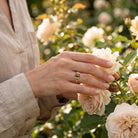 [KI] Silberring mit Tigerauge an der Hand zwischen Blumen