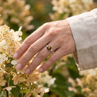 [KI] Silberring mit Tigerauge an der Hand zwischen Blumen