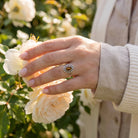 [KI] Silberring mit Tigerauge an der Hand zwischen Blumen
